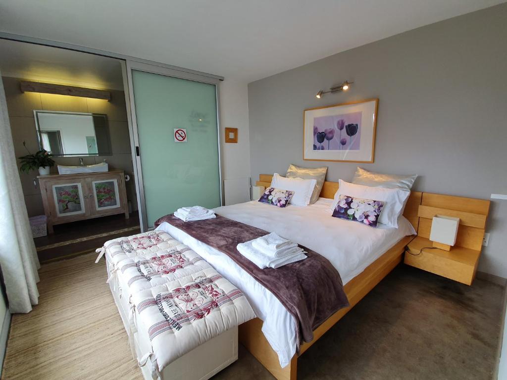 1 dormitorio con 1 cama grande y espejo en Lind End Guest Farm en Haenertsburg
