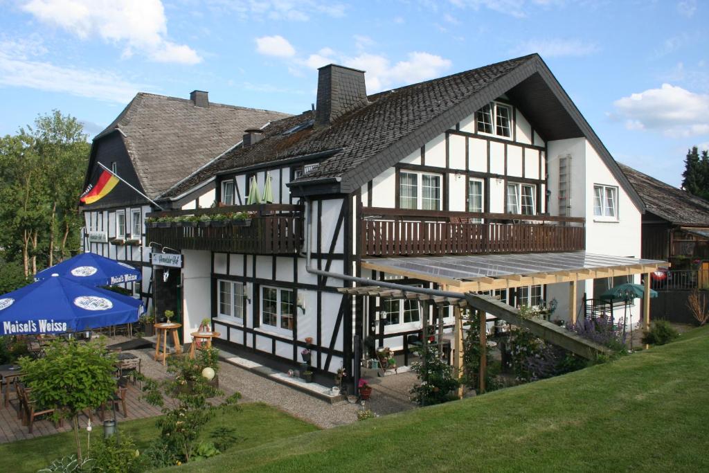 ein großes weißes und schwarzes Haus mit einer Terrasse in der Unterkunft Hennetaler Hof in Erflinghausen