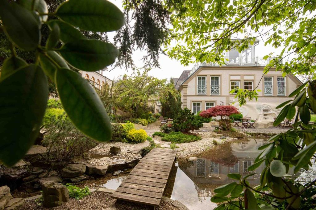 un jardín con un puente de madera frente a una casa en Garten-Hotel Ochensberger, en Sankt Ruprecht an der Raab