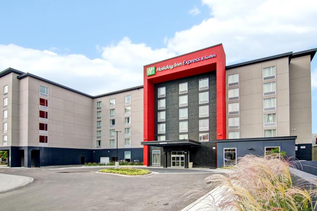 オシャワにあるHoliday Inn Express & Suites Oshawa Downtown - Toronto Area, an IHG Hotelの赤い看板のホテルの建物
