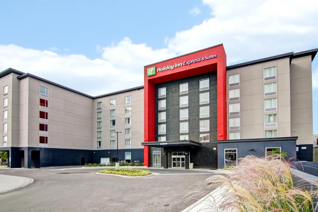 ein Hotelgebäude mit einem roten Schild darauf in der Unterkunft Holiday Inn Express & Suites Oshawa Downtown - Toronto Area, an IHG Hotel in Oshawa