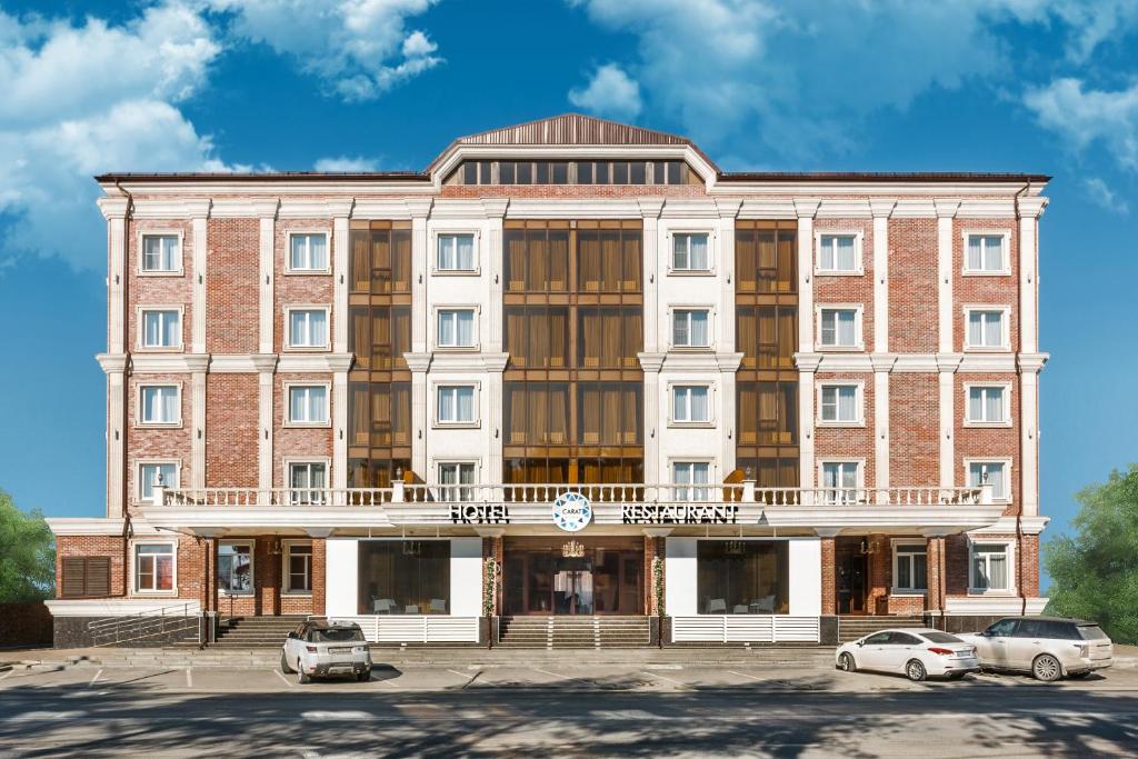 a large brick building with cars parked in a parking lot at Carat by Undersun in Krasnodar