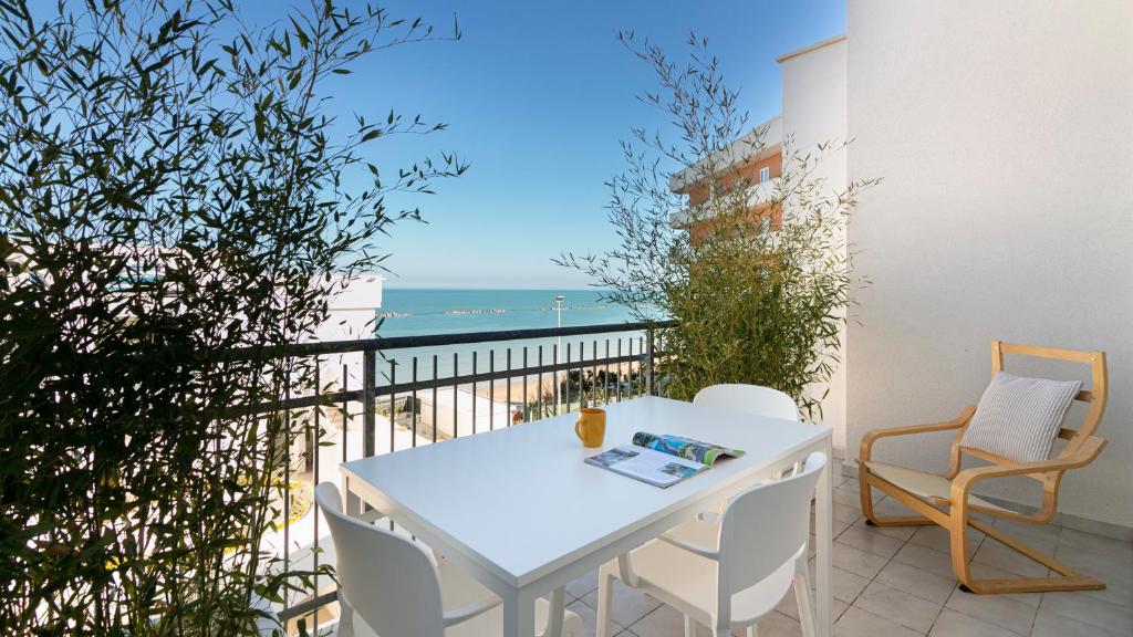 - une table et des chaises blanches sur un balcon donnant sur l'océan dans l'établissement Rivazzurra Homes - B, à Termoli