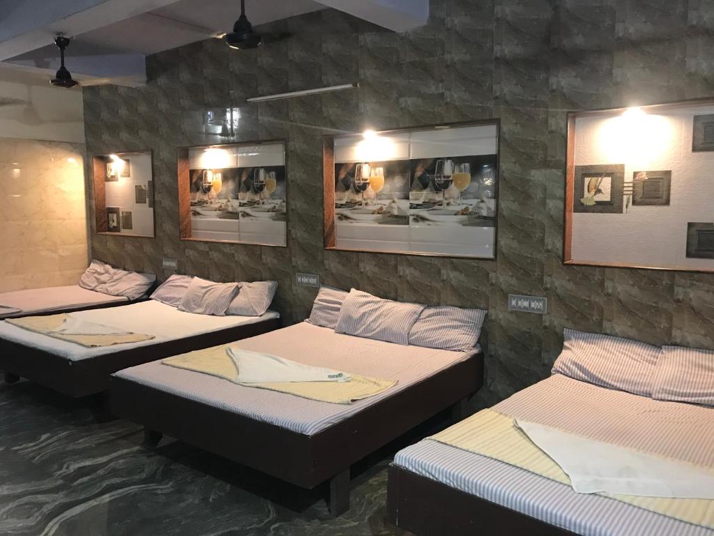 drie bedden in een kamer met een stenen muur bij Hotel Rehoboth in Kanyakumari