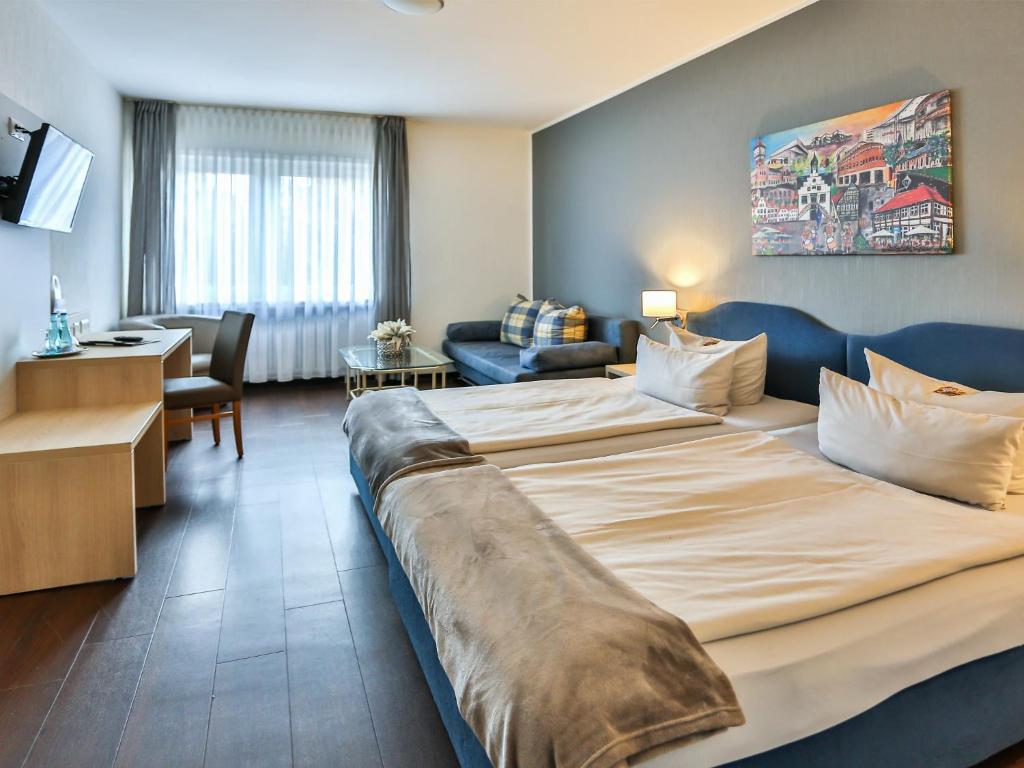 a hotel room with a large bed and a living room at Hotel-Restaurant Kolpinghaus in Lingen