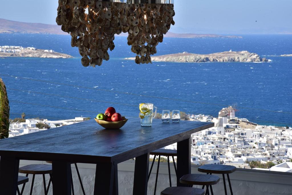 a table with a bowl of fruit on top of a balcony at Hermes Mykonos Hotel in Mikonos