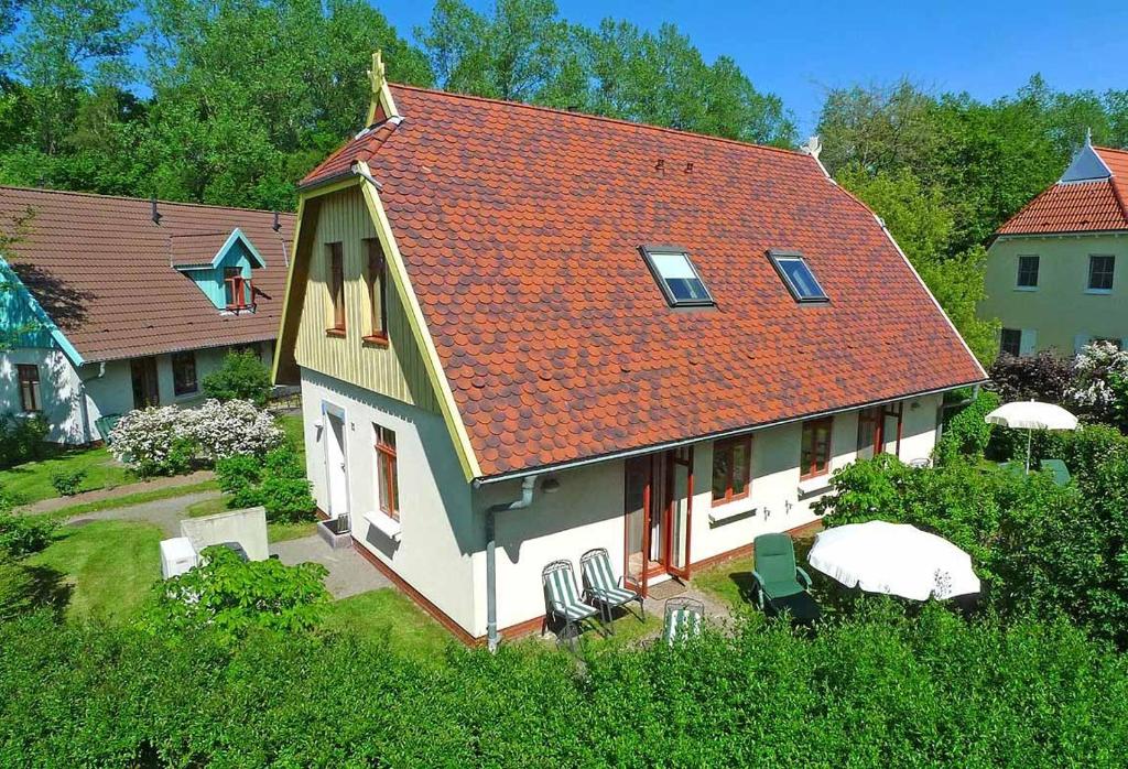 een huis met een oranje dak met stoelen en tafels bij Ferienhaussiedlung Strandperlen Buchenhof 3a (Typ III) in Wustrow