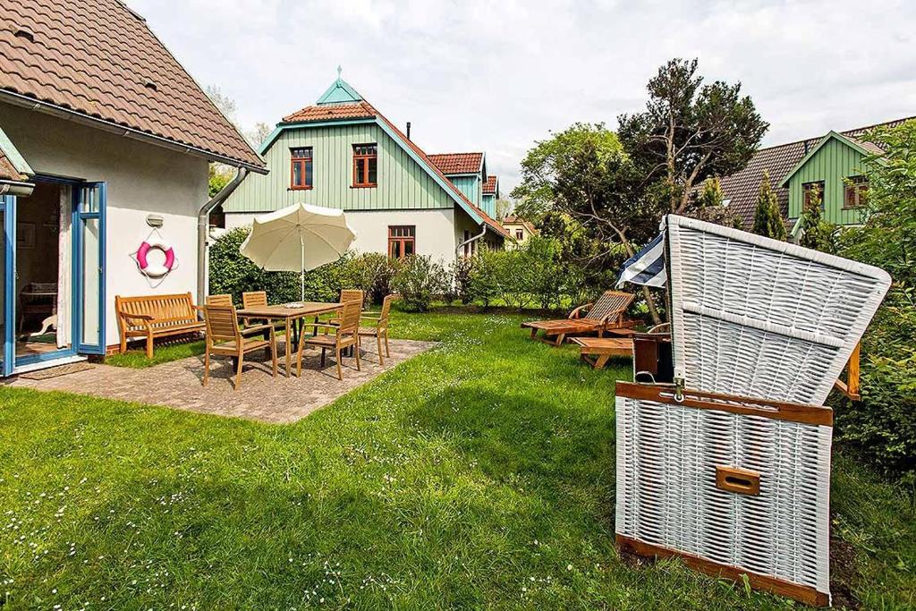 einen Hinterhof mit einem Tisch, Stühlen und einem Sonnenschirm in der Unterkunft Ferienhaussiedlung Strandperlen Weidenhof 7b (Typ VII) in Wustrow