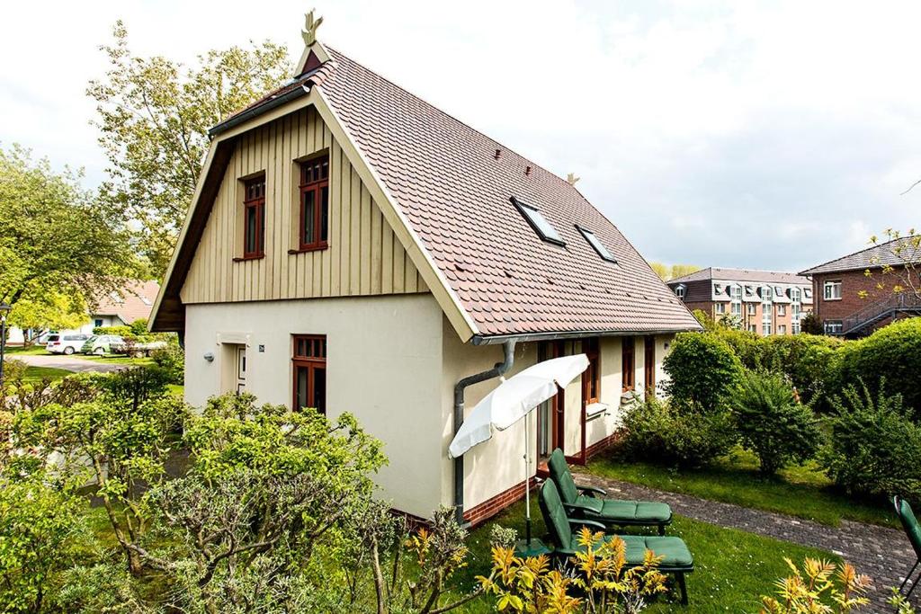 a small white house with a gambrel roof at Ferienhaussiedlung Strandperlen Weidenhof 2a (Typ III) in Wustrow