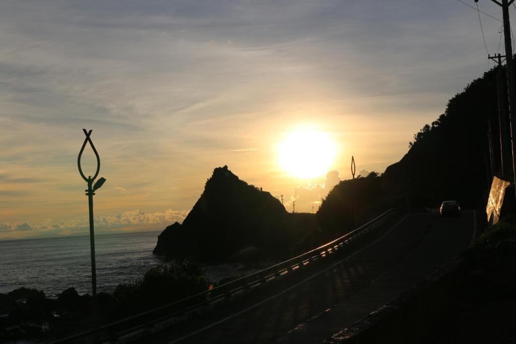a sun setting over the ocean next to a road at Banai Homestay in Lanyu