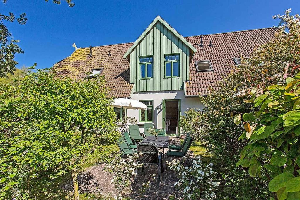 ein Haus mit einem Tisch und Stühlen im Hof in der Unterkunft Ferienhaussiedlung Strandperlen Weidenhof 3b (Typ VI) in Wustrow