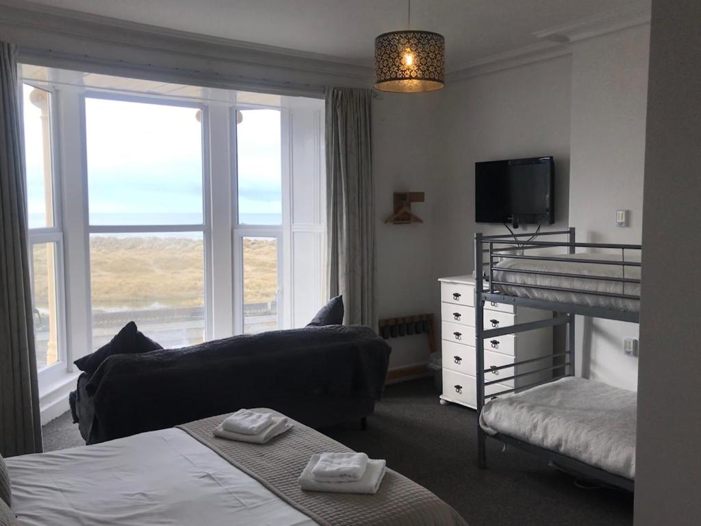 a bedroom with a bunk bed and a couch and a television at The Sandpiper in Barmouth