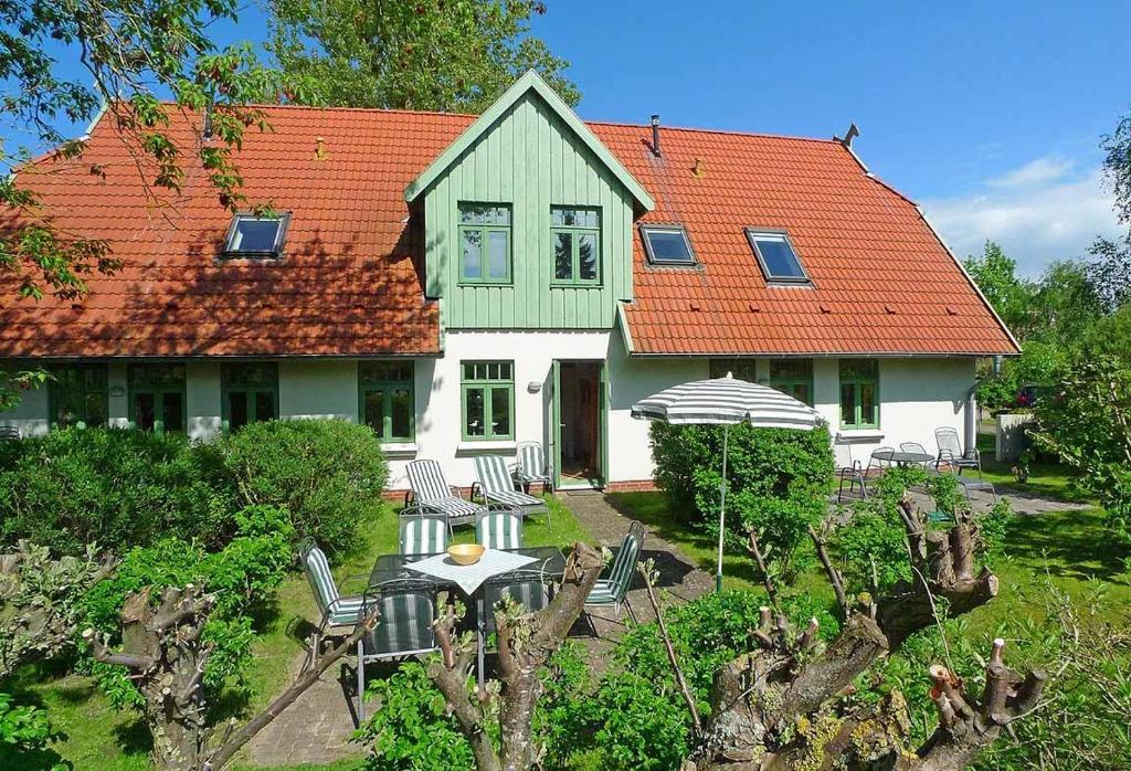 una casa con techo naranja, mesa y sillas en Ferienhaussiedlung Strandperlen Sanddornhof 3b (Typ VI), en Wustrow