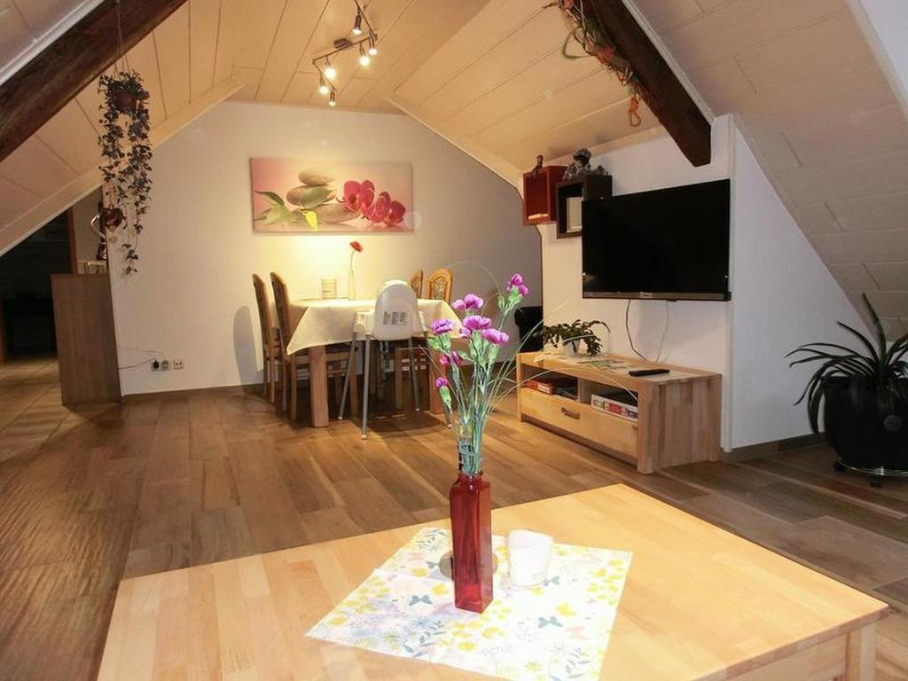 a living room with a table and a vase with flowers in it at Altes Forsthaus in Bad Peterstal-Griesbach