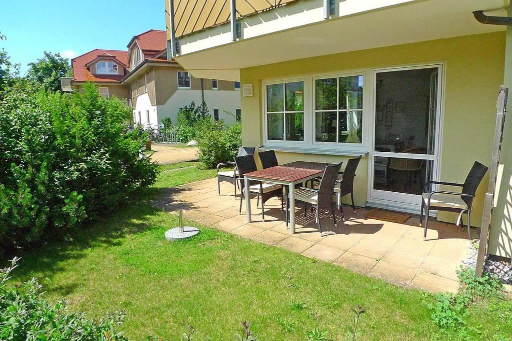 a patio with a table and chairs next to a house at BIRKENHOF Whg. BH-41 in Wustrow