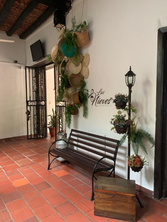 un banco en una habitación con plantas en la pared en Hotel Las Nieves, en Girón