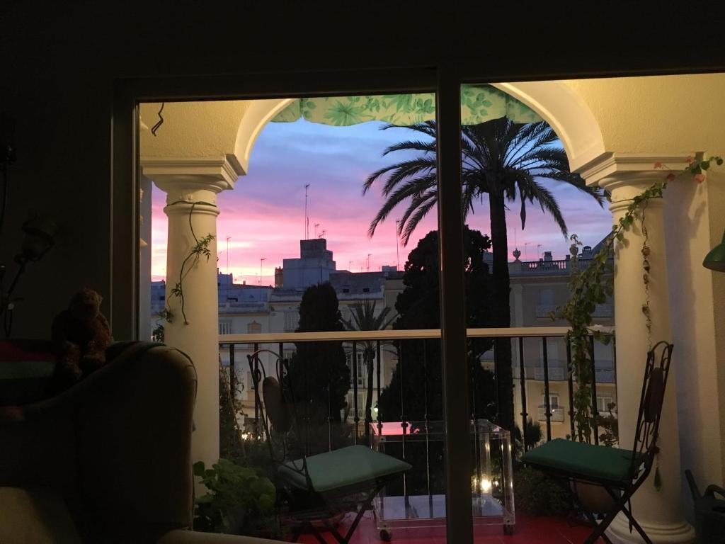 a view of a sunset from a balcony with a palm tree at Casa de Plaza Candelaria Rooms in Cádiz