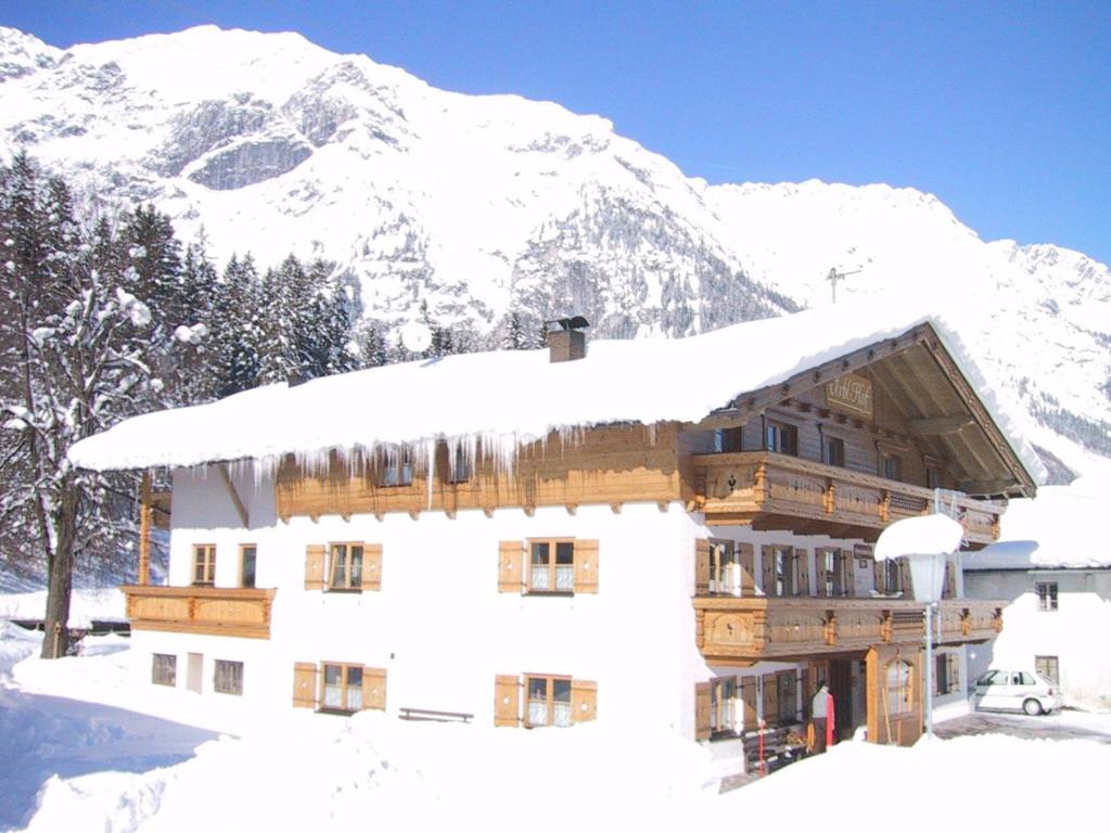 ein schneebedecktes Gebäude mit einem Berg im Hintergrund in der Unterkunft Urblhof in Leutasch