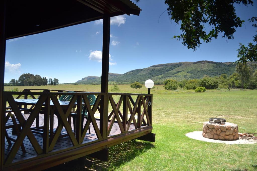 a deck with a fire pit and mountains in the background at Intaba Thulile in Maanhaarrand