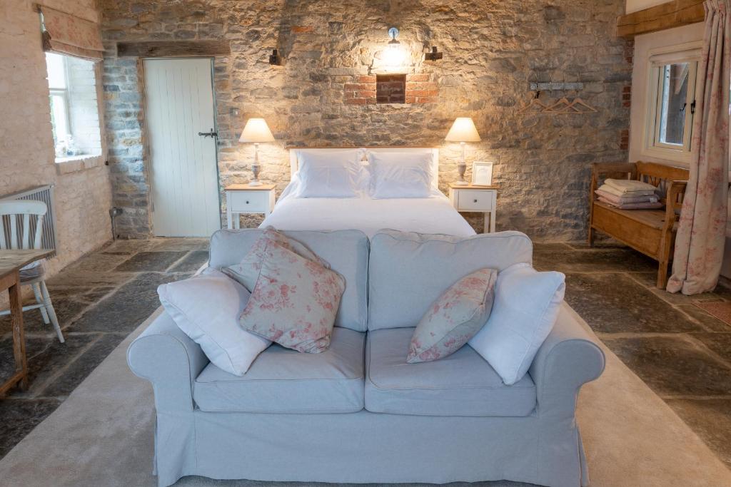1 dormitorio con 1 cama y 1 sofá con almohadas en The Barn at Amberwell, en Ditcheat