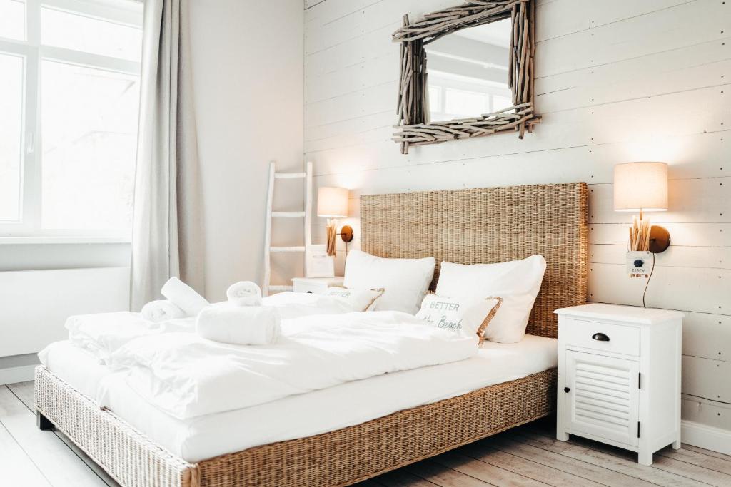 a bedroom with a large white bed and a mirror at BeachBude Apartments in Timmendorfer Strand