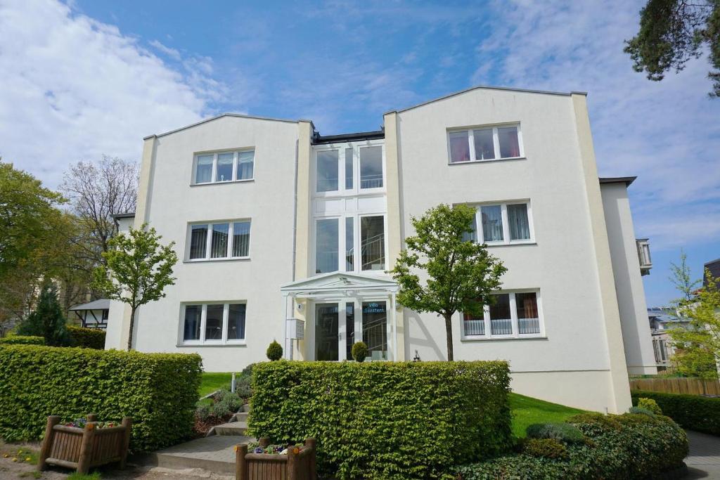 una casa blanca con arbustos delante en Villa Seestern _ Wohnung 2, en Neuhof