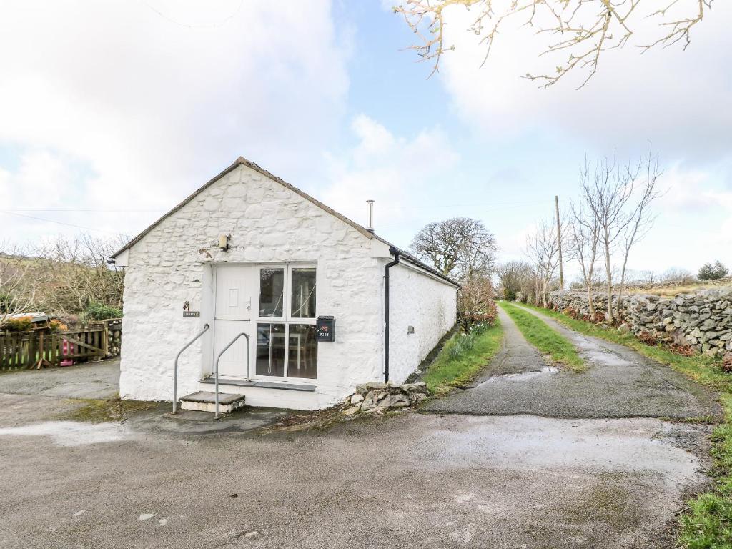 a white building with a door on a road at Y Buarth in Caernarfon