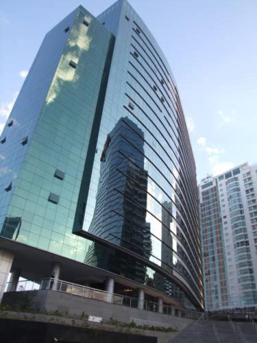 a tall glass building in a city with tall buildings at VISION HOTEL Brasilia Piscina Academia Garagem Flat 12 Andar in Brasília