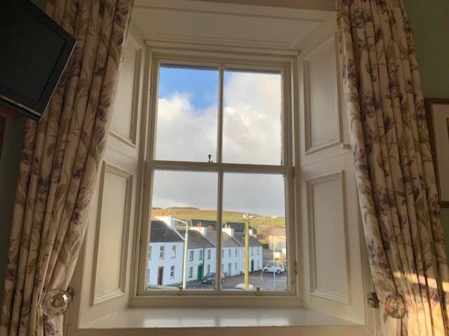 an open window with a view of a building at Port Charlotte Hotel in Port Charlotte