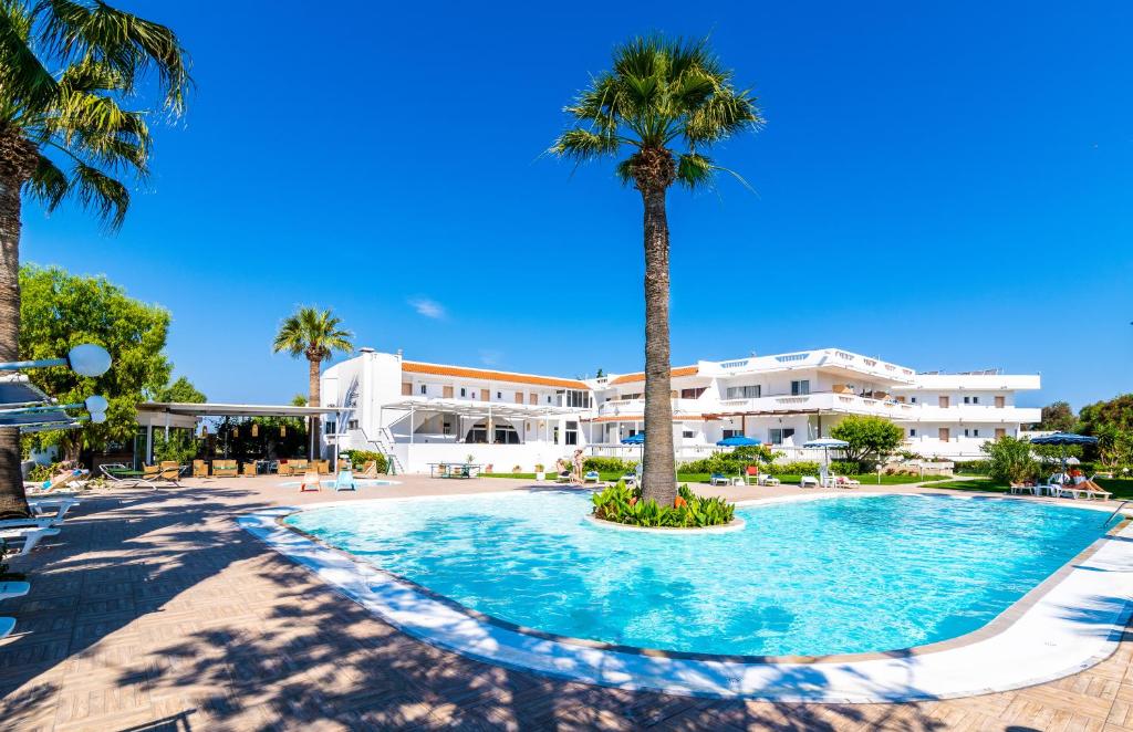 a swimming pool with a palm tree in front of a building at Sabina Hotel in Theologos