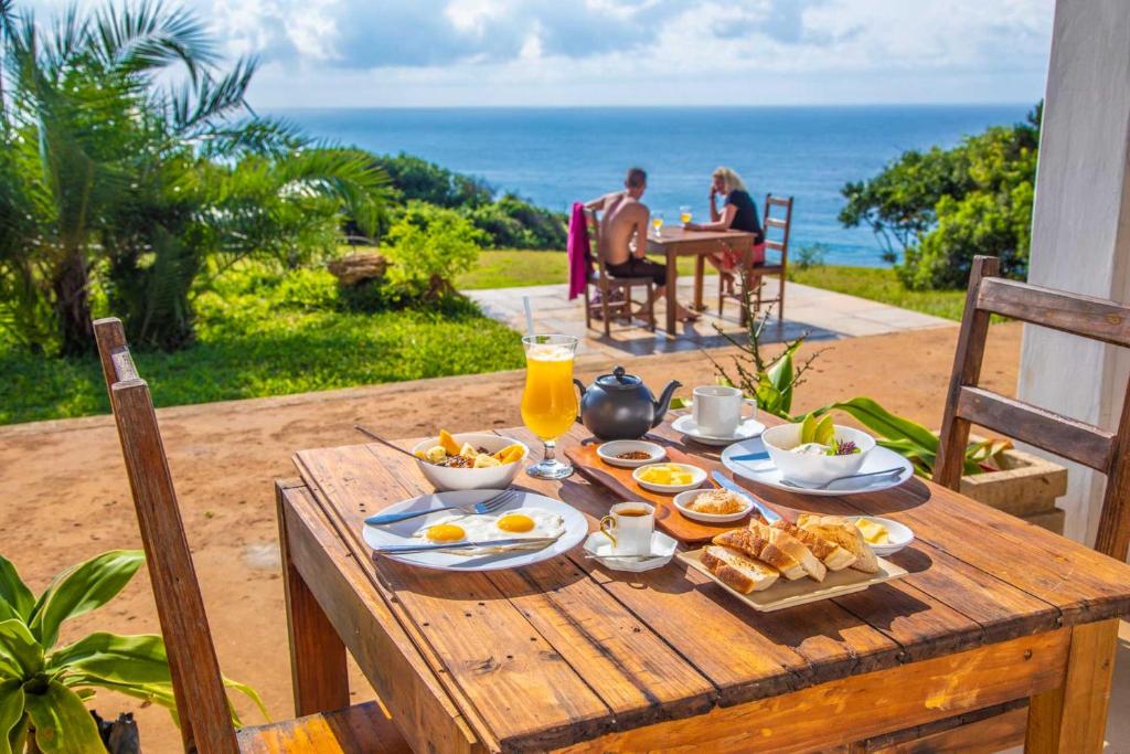 a wooden table with breakfast food on it with the ocean at Sky Island Resort in Ponta Malongane