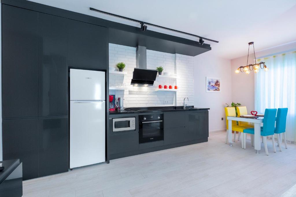uma cozinha com armários pretos e um frigorífico branco em Twin Apart Hotel em Alanya