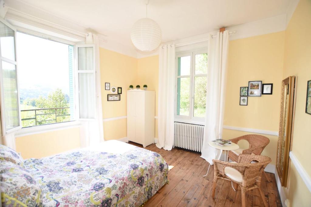 1 dormitorio con cama, mesa y ventanas en Le Coteau d'Olliergues, en Olliergues