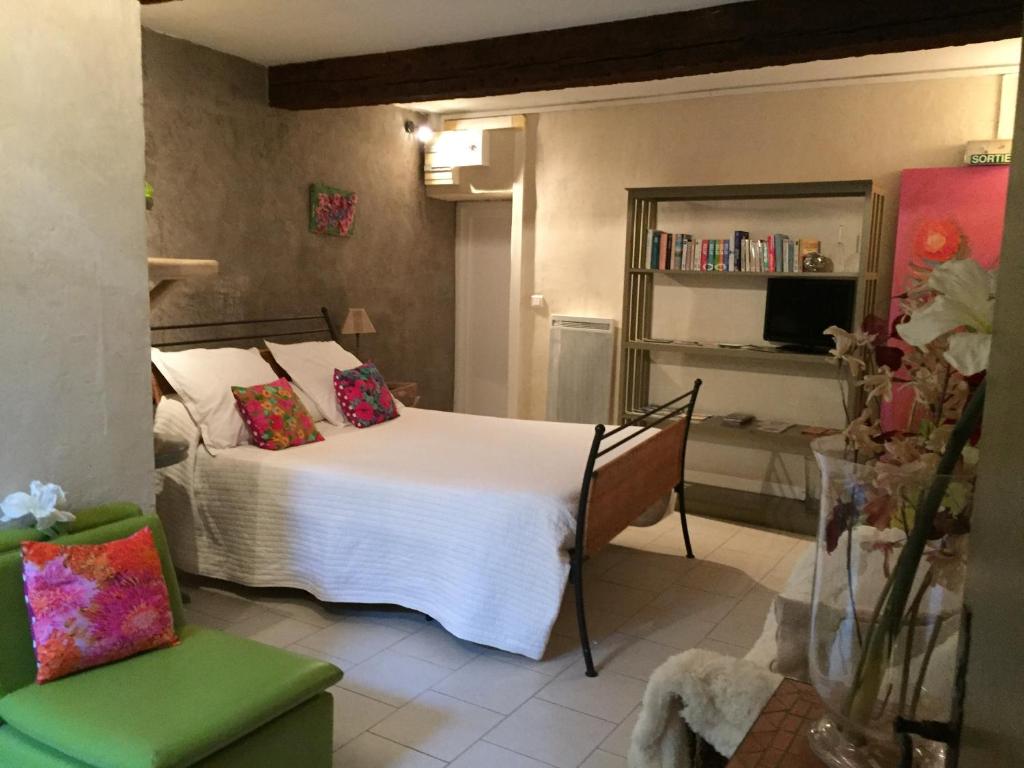 a bedroom with a white bed and a green chair at La Maison du Bien Etre in Aigues-Mortes