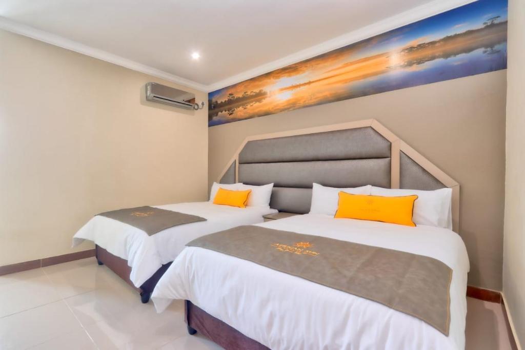 2 camas en una habitación con un cuadro en la pared en African Sun lodge, en Durban