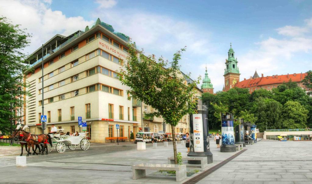 una calle de la ciudad con un carruaje de caballos y un edificio en Hotel Pod Wawelem en Cracovia