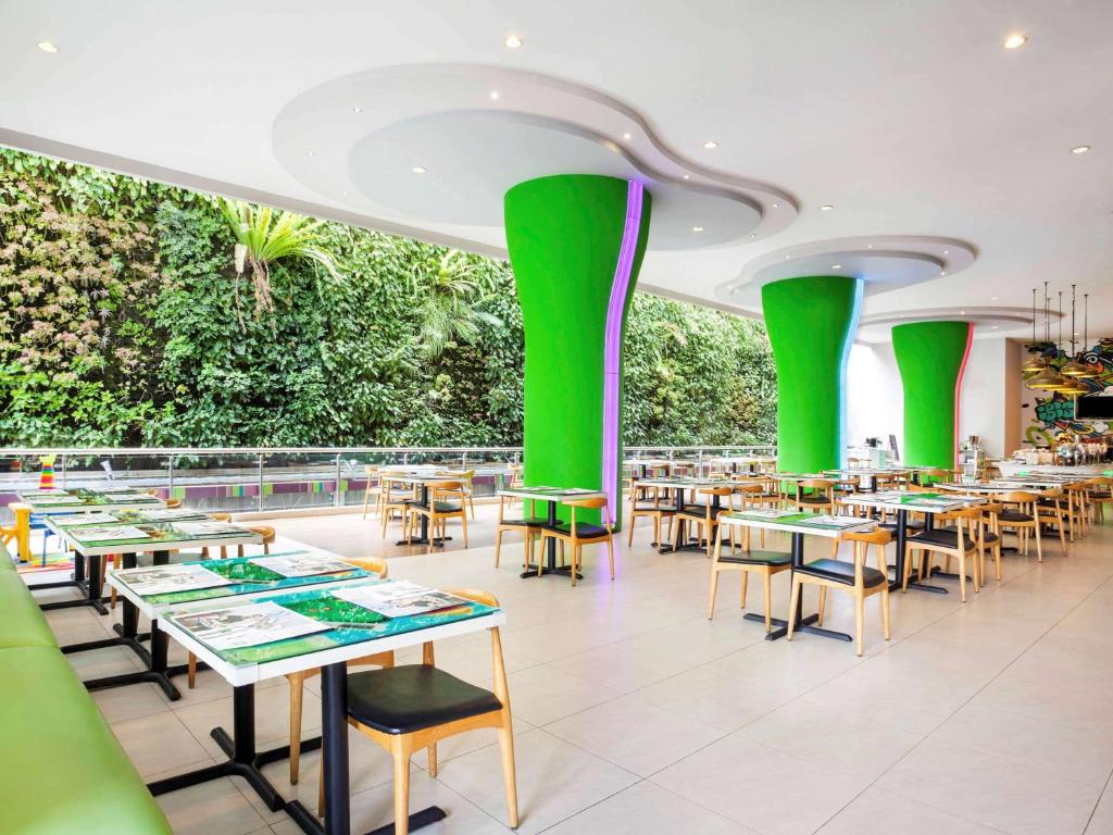 un comedor con mesas y columnas verdes en Ibis Styles Malang en Malang