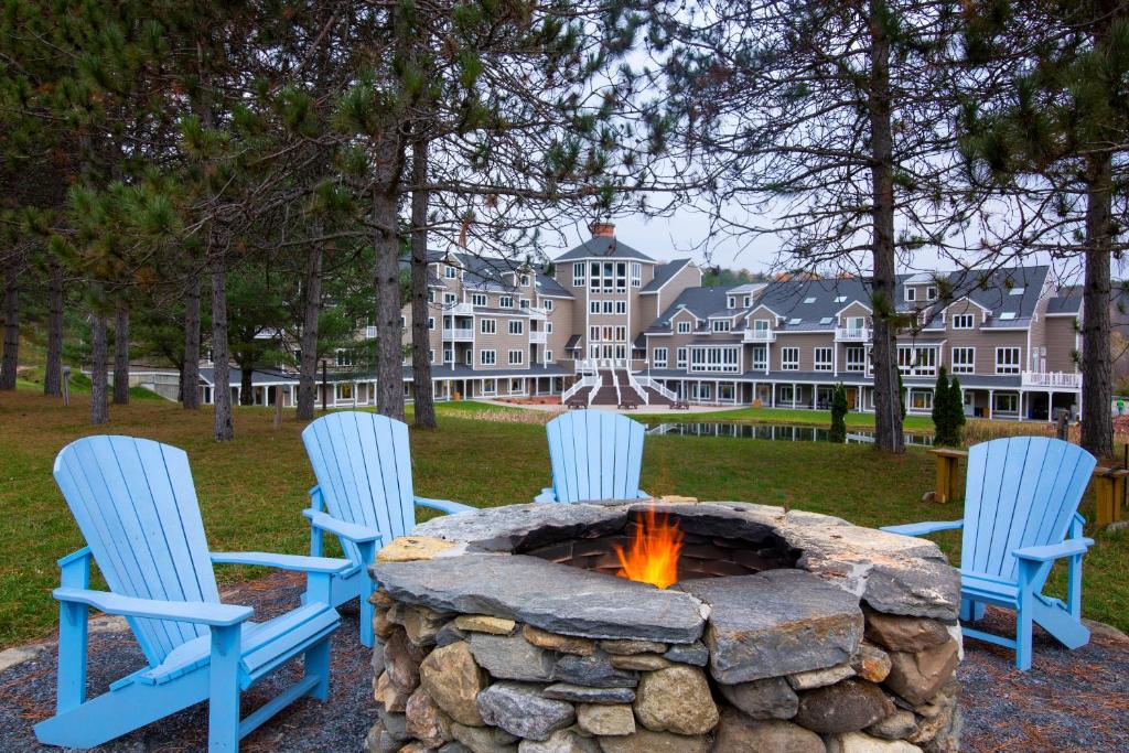 three chairs around a stone fire pit in a yard at Holiday Inn Club Vacations Mount Ascutney Resort in Brownsville