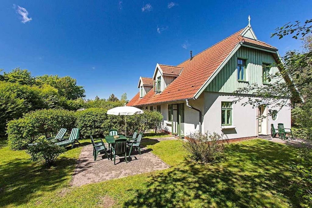 a house with a table and chairs in the yard at Ferienhaussiedlung Strandperlen Küstenhof 1d (Typ IV) in Wustrow