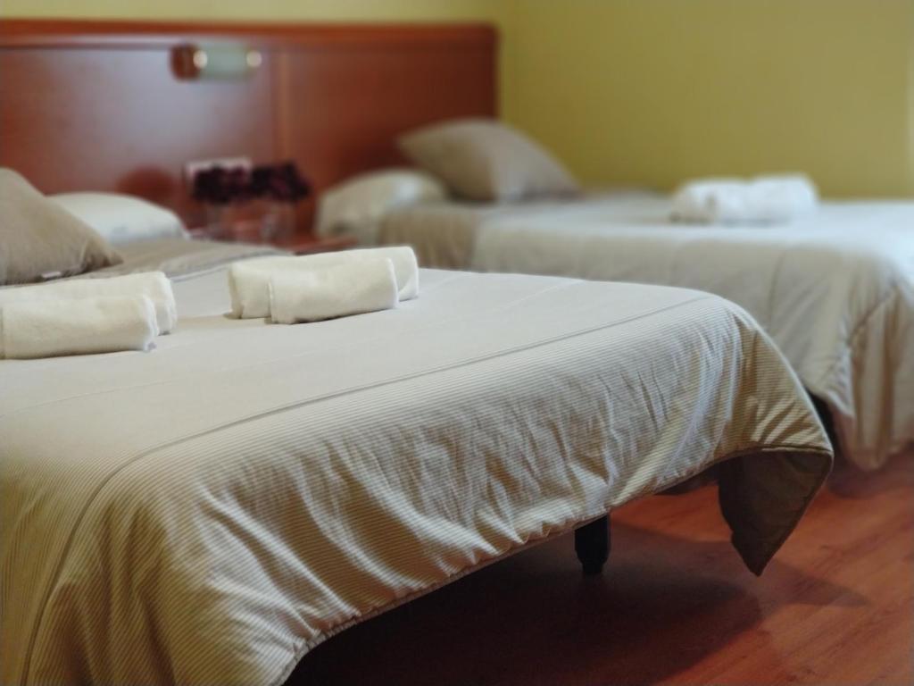 2 Betten mit weißer Bettwäsche und Kissen in einem Zimmer in der Unterkunft Hostal Restaurante Iruñako in Burgos