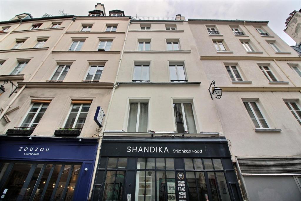 un grand bâtiment avec un magasin devant lui dans l'établissement 102467 - Appartement 1 Chambre Montorgueil, à Paris