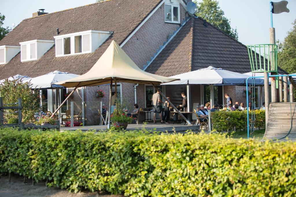 un groupe de personnes assis sous des parasols à l'extérieur d'une maison dans l'établissement Recreatiecentrum de Kluft, à Ossenzijl