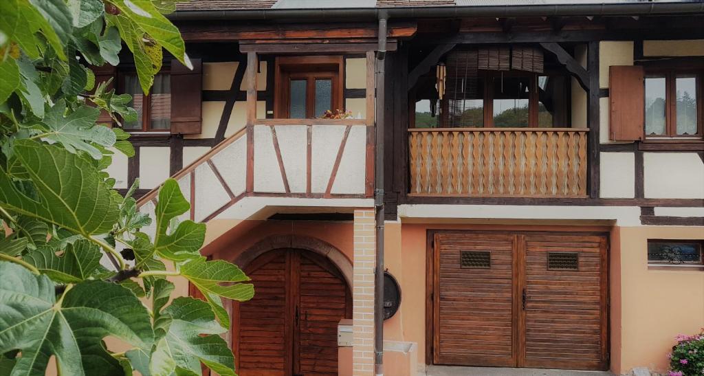 um edifício com duas portas de madeira e uma varanda em La Valériane em Kintzheim