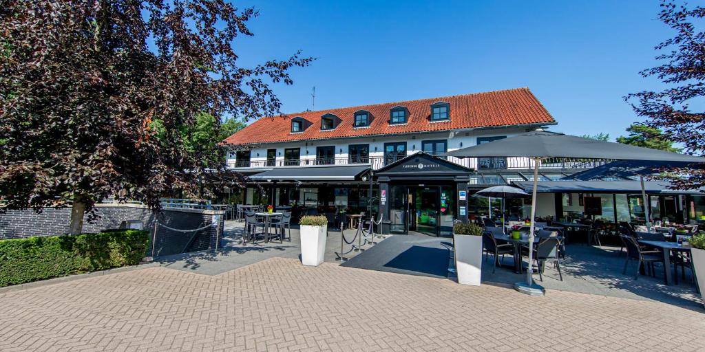 un edificio con un patio al aire libre con mesas y sombrillas en Fletcher Hotel-Restaurant Jagershorst-Eindhoven, en Leende