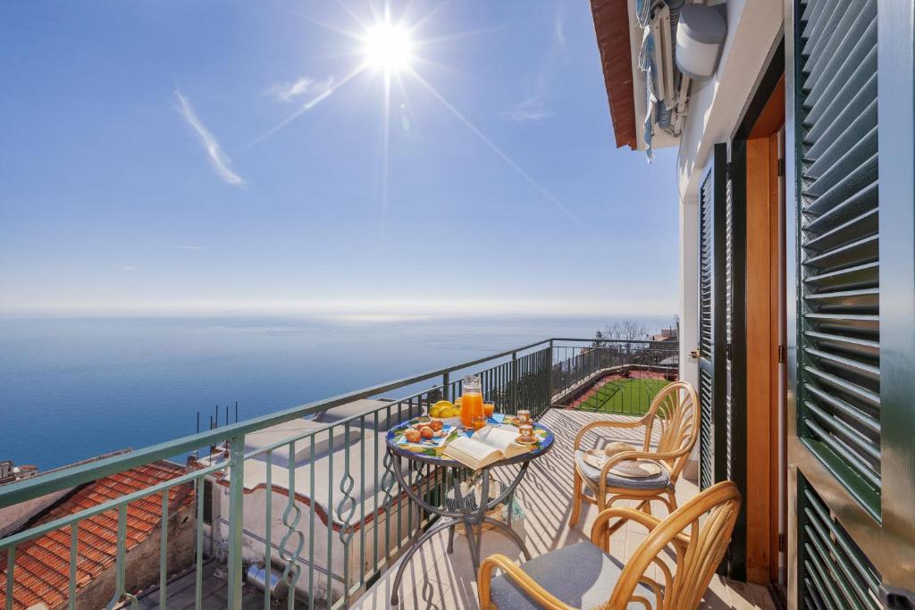 einen Balkon mit einem Tisch, Stühlen und Meerblick in der Unterkunft AMORE RENTALS - Residenza Rosalia 1 in Ravello