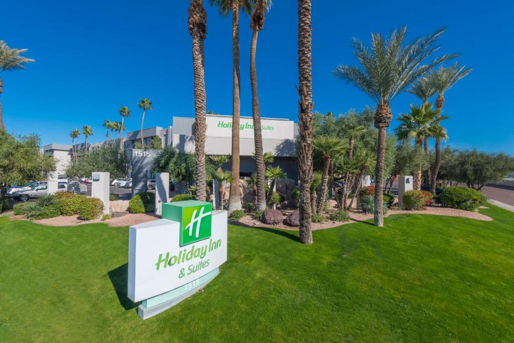 Holiday Inn and Suites Phoenix Airport North, an IHG Hotel في فينكس: لافته امام الفندق عليها نخيل