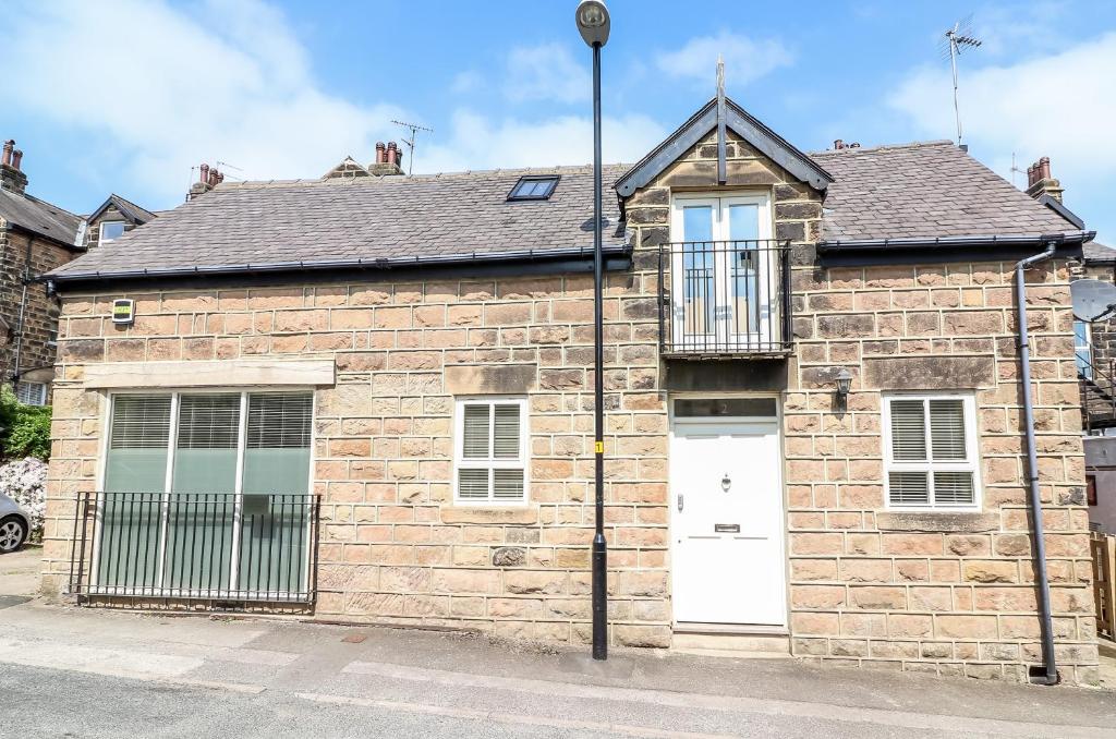 a brick building with a white door on a street at Harlow Coach House in Harrogate