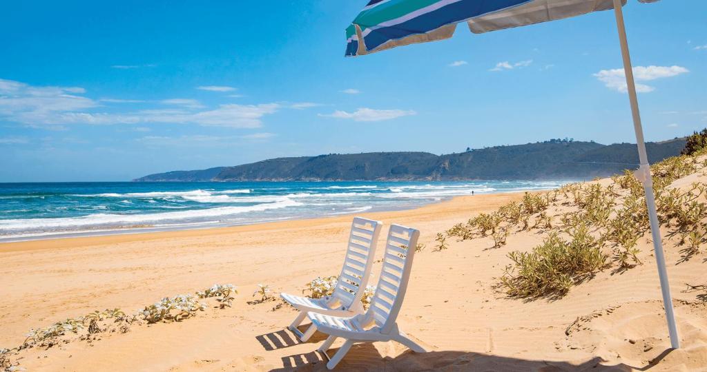 a beach chair and an umbrella on a beach at Shan C in Wilderness