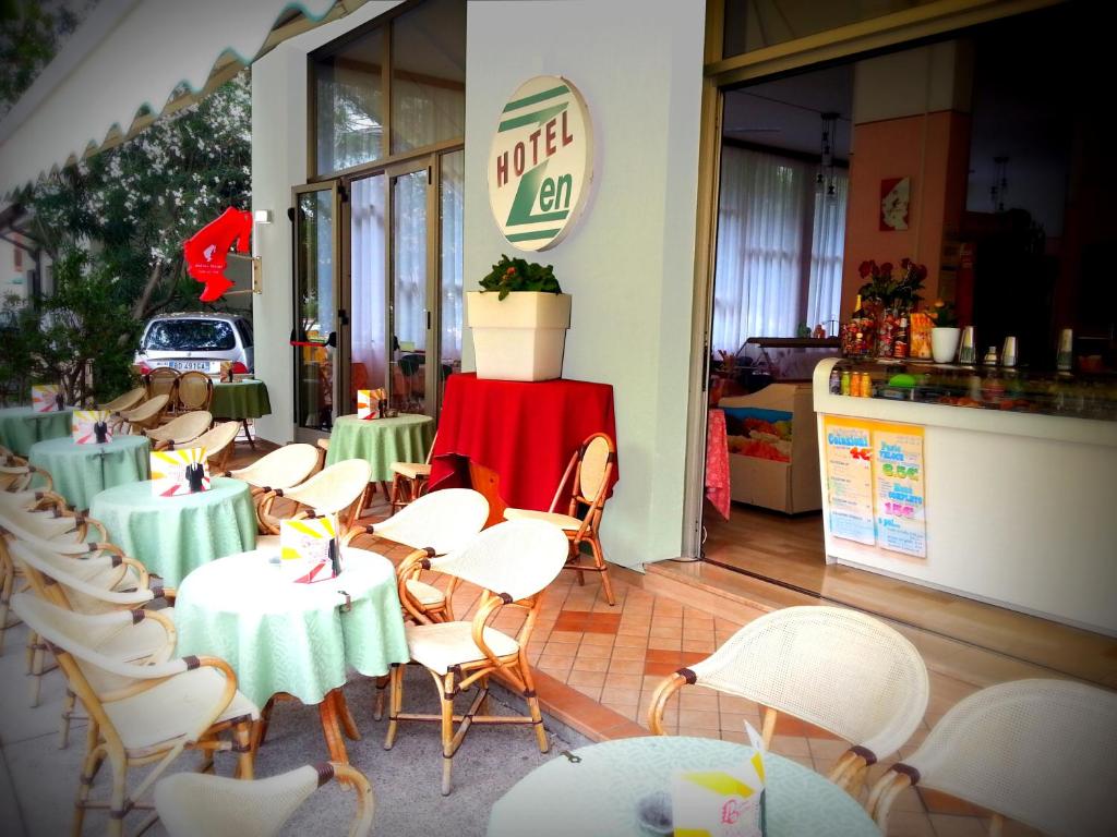 un ristorante con tavoli verdi e sedie bianche di Hotel Zen a Lignano Sabbiadoro