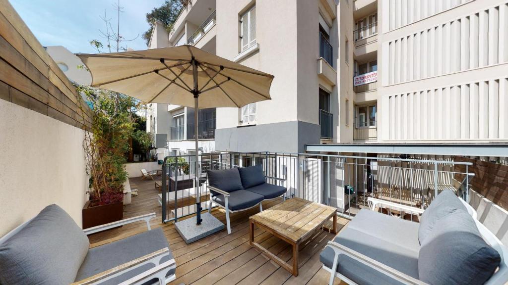 a patio with a table and an umbrella on a balcony at Villa Shira by HolyGuest in Tel Aviv